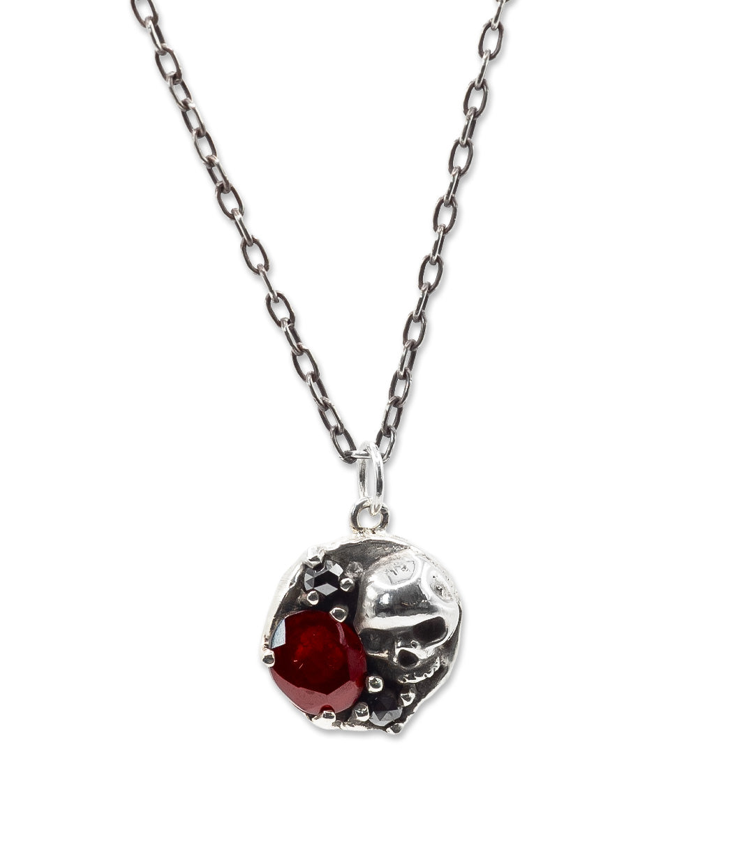 Silver necklace with a heart-shaped pendant featuring a red gemstone on a white background