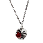 Silver necklace with a heart-shaped pendant featuring a red gemstone on a white background