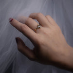 Hand wearing a ring with a diamond on a light gray background