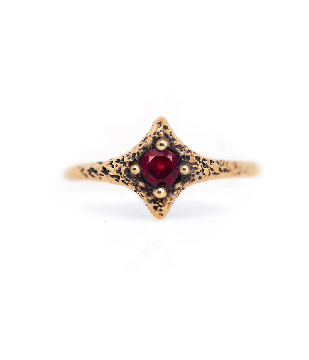 Gold ring with a red gemstone on a white background