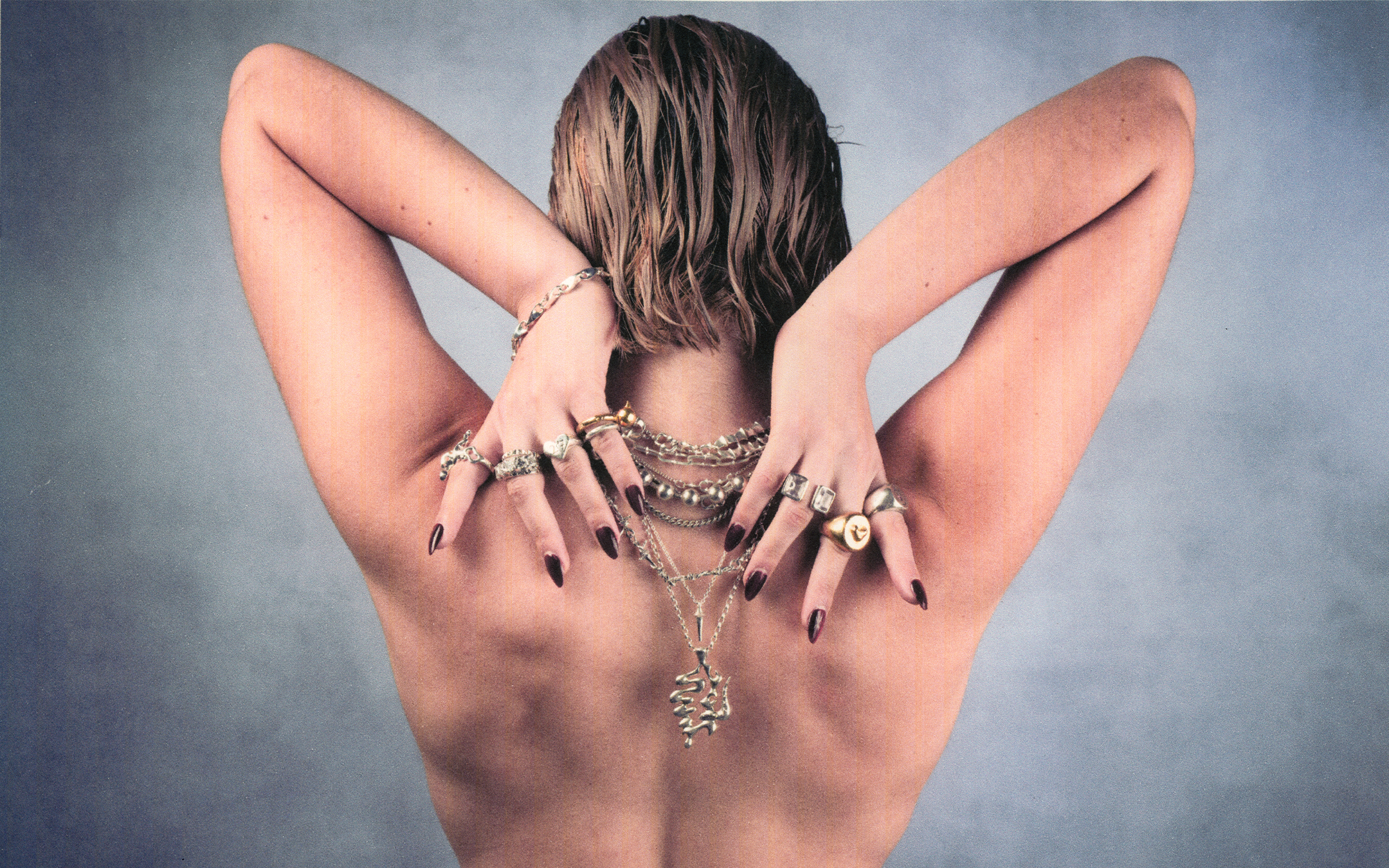 Woman with multiple necklaces and rings on a gray background