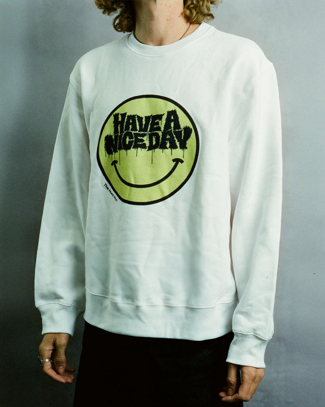 White sweatshirt with a smiley face and 'Have a nice day' text on a gray background