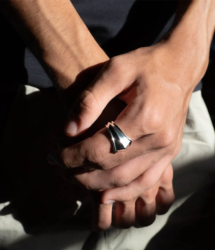 Close-up of a hand wearing a silver ring with a dark background