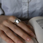 Hand wearing a silver ring on an open book with a blurred background