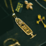 Gold pendant with intricate design on a dark background