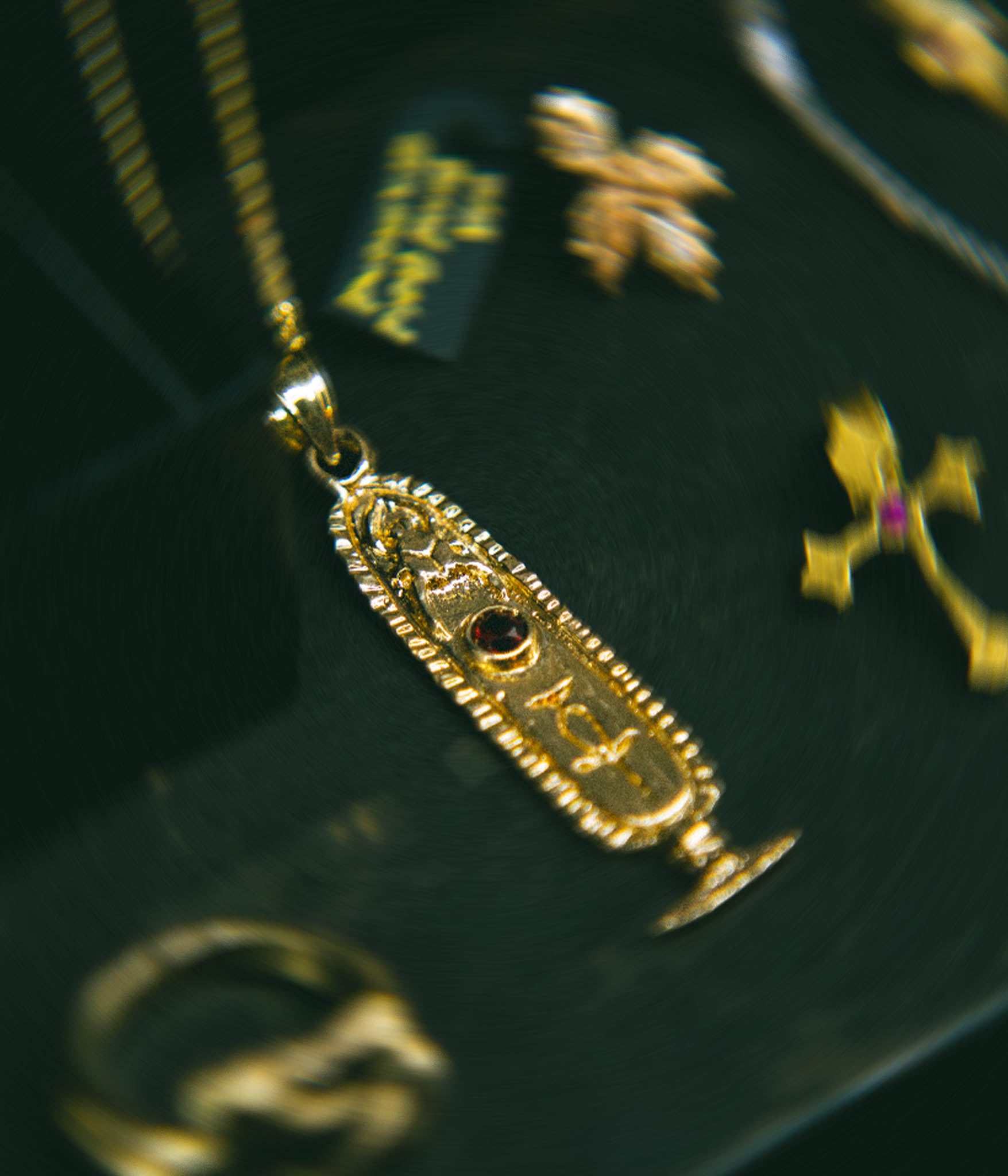 Gold pendant with intricate design on a dark background