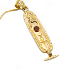 Gold pendant with an Egyptian design on a white background