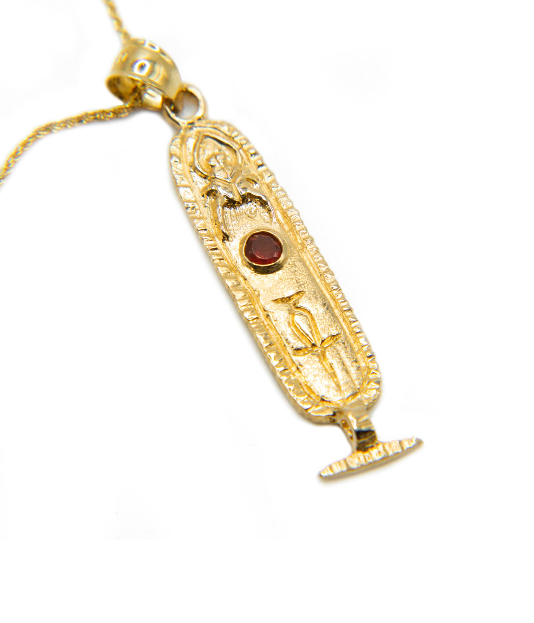 Gold pendant with an Egyptian design on a white background