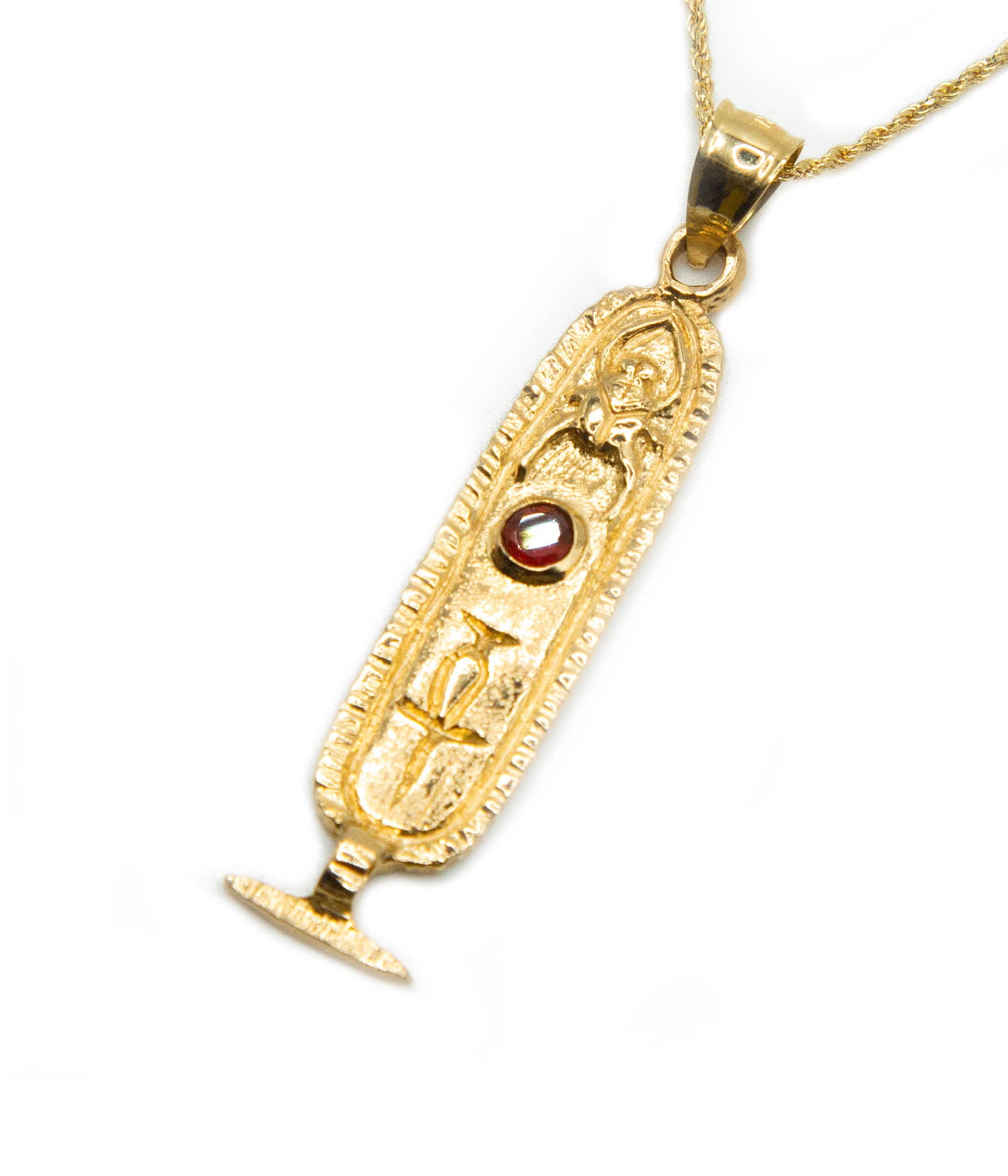 Gold pendant with a red gemstone on a white background
