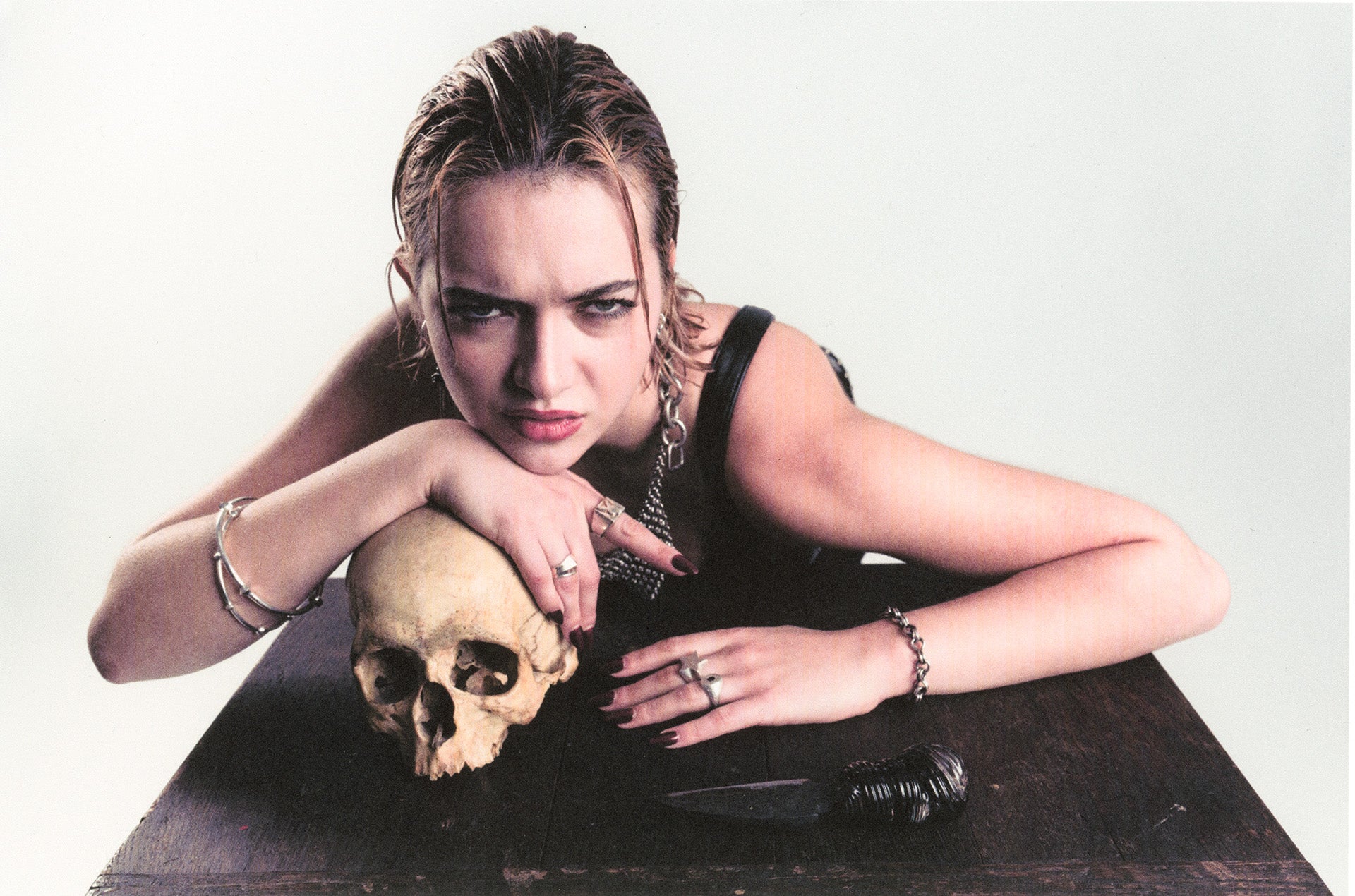 Woman with a skull on a table against a white background