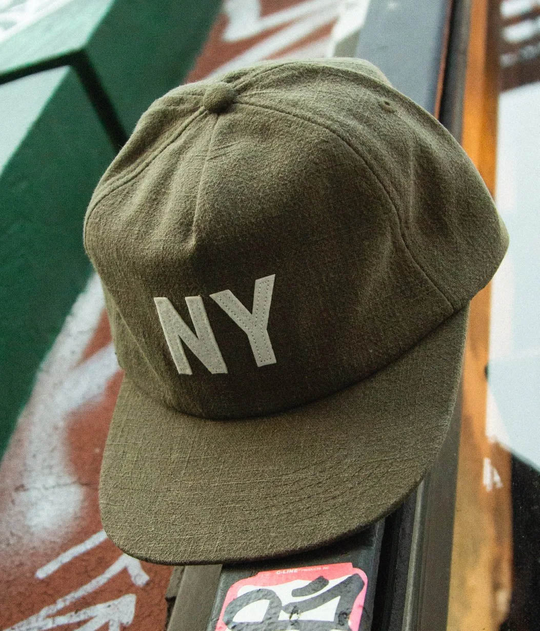 Green cap with 'NY' on a textured surface