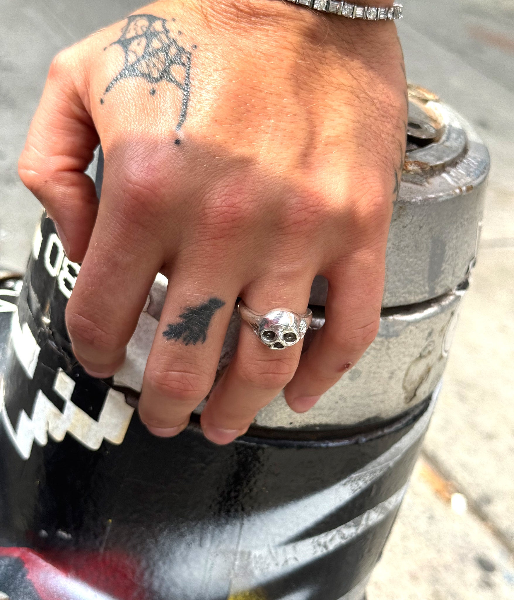 Hand with tattoos and a silver ring on a cylindrical object