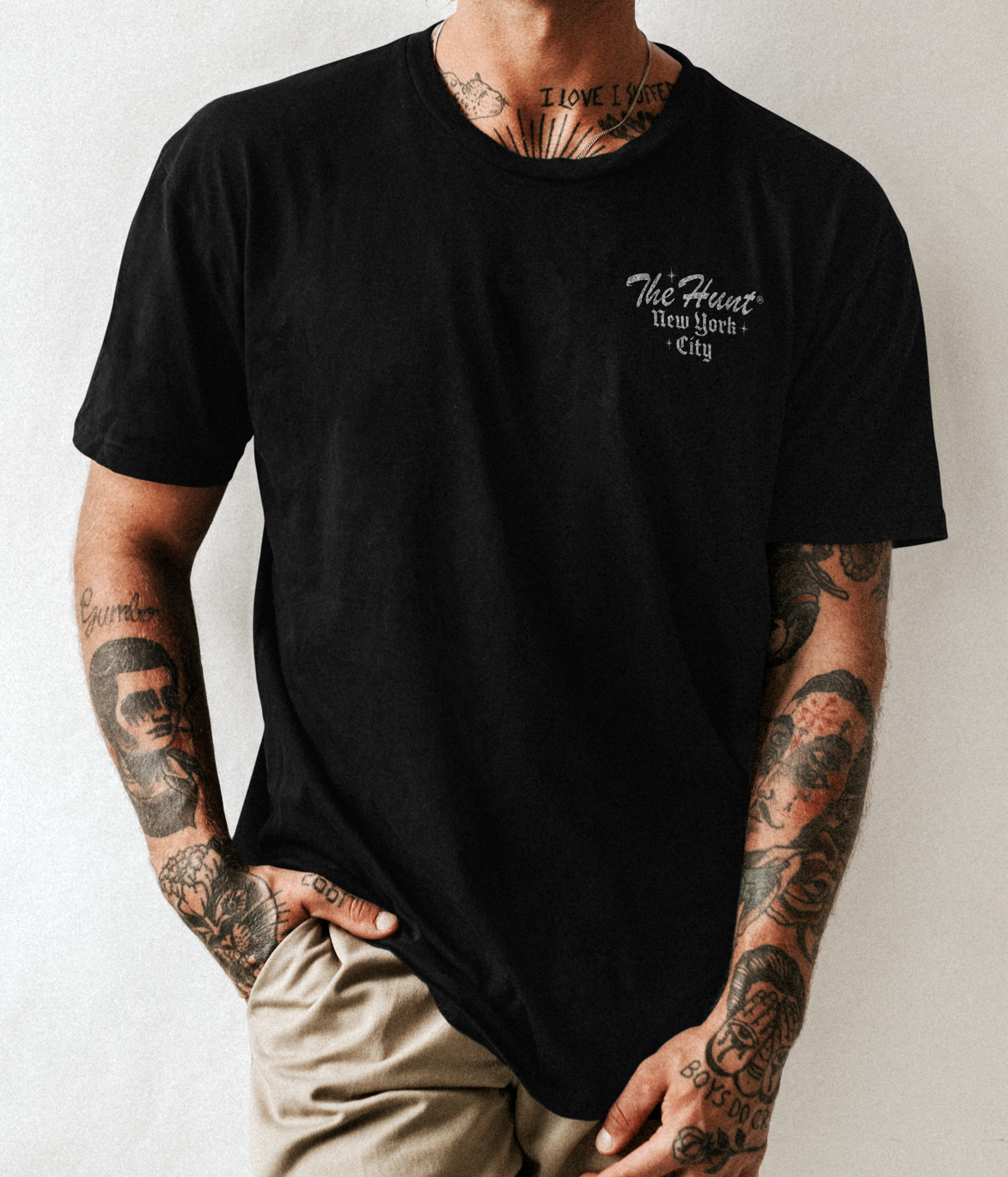 Person wearing a black t-shirt with text, standing against a plain background