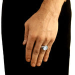 Hand wearing a silver ring with a clear stone on a black background