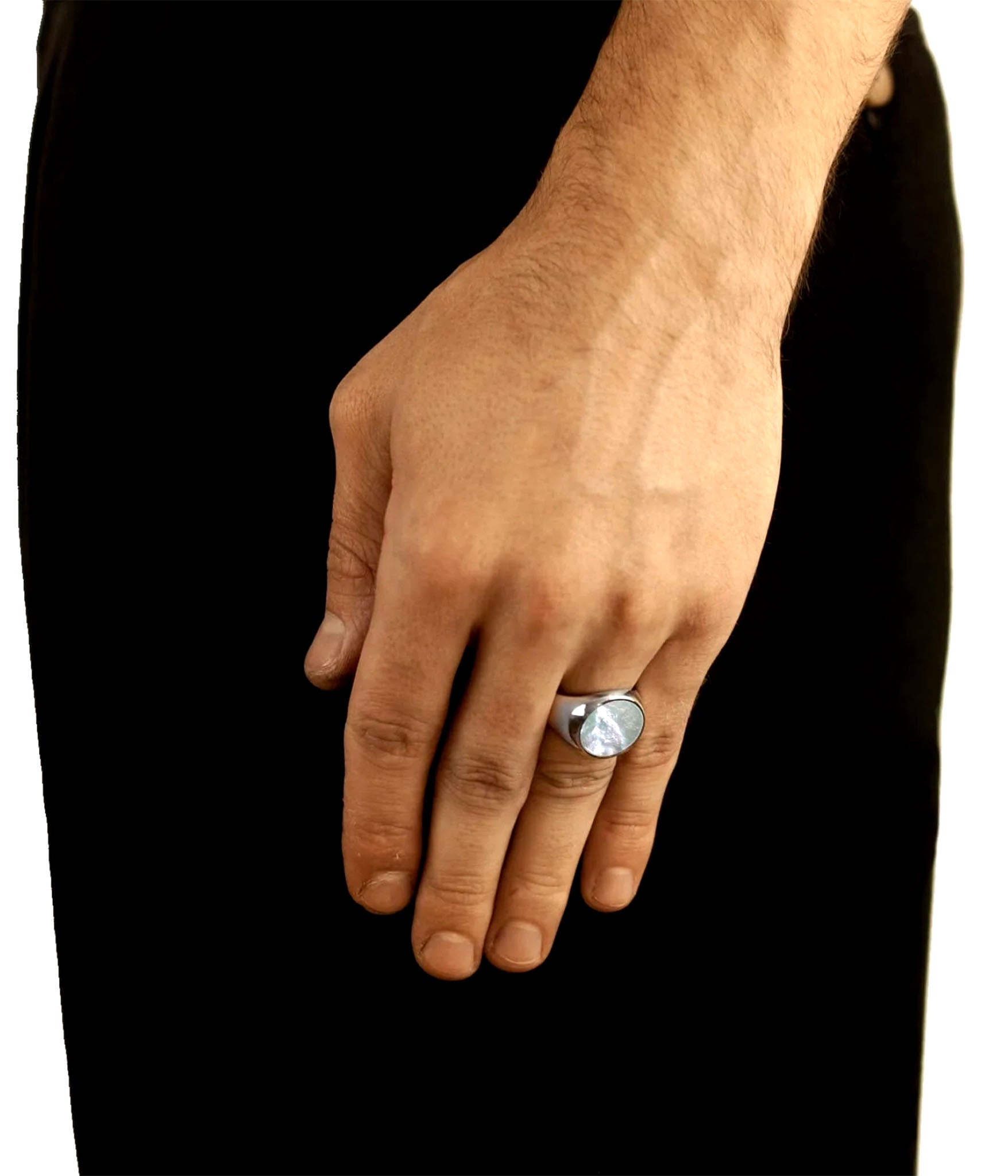 Hand wearing a silver ring with a clear stone on a black background