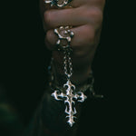 Hand wearing multiple silver rings with intricate designs on a dark background