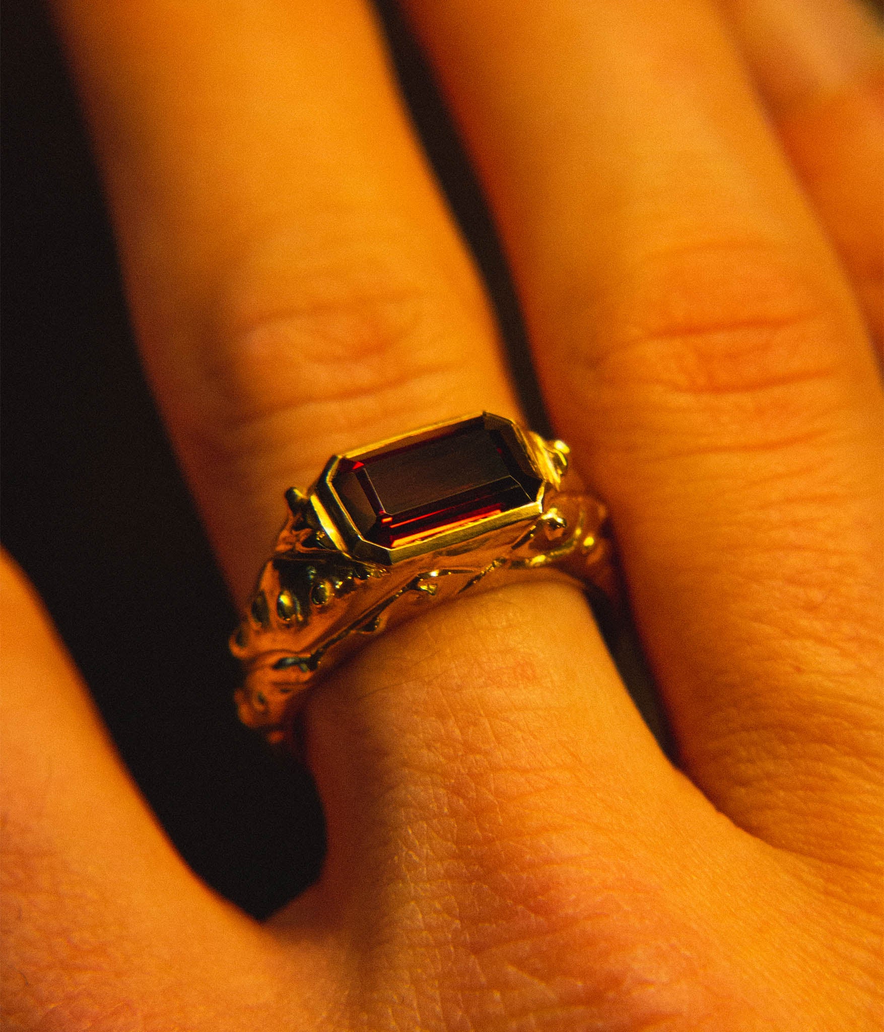 Gold ring with a red gemstone on a finger