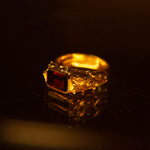 Gold ring with a red gemstone on a dark background
