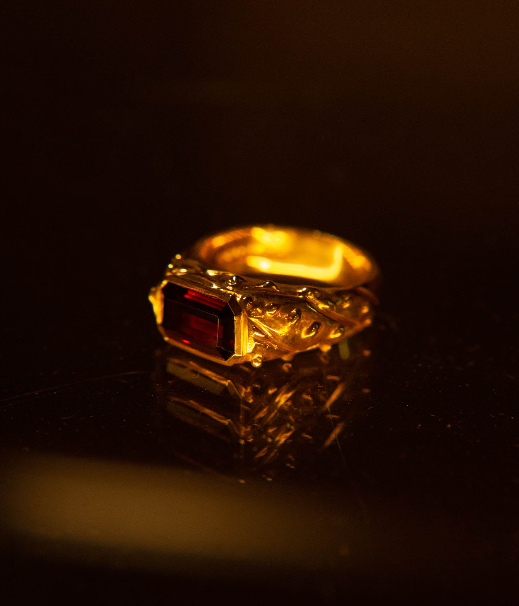 Gold ring with a red gemstone on a dark background