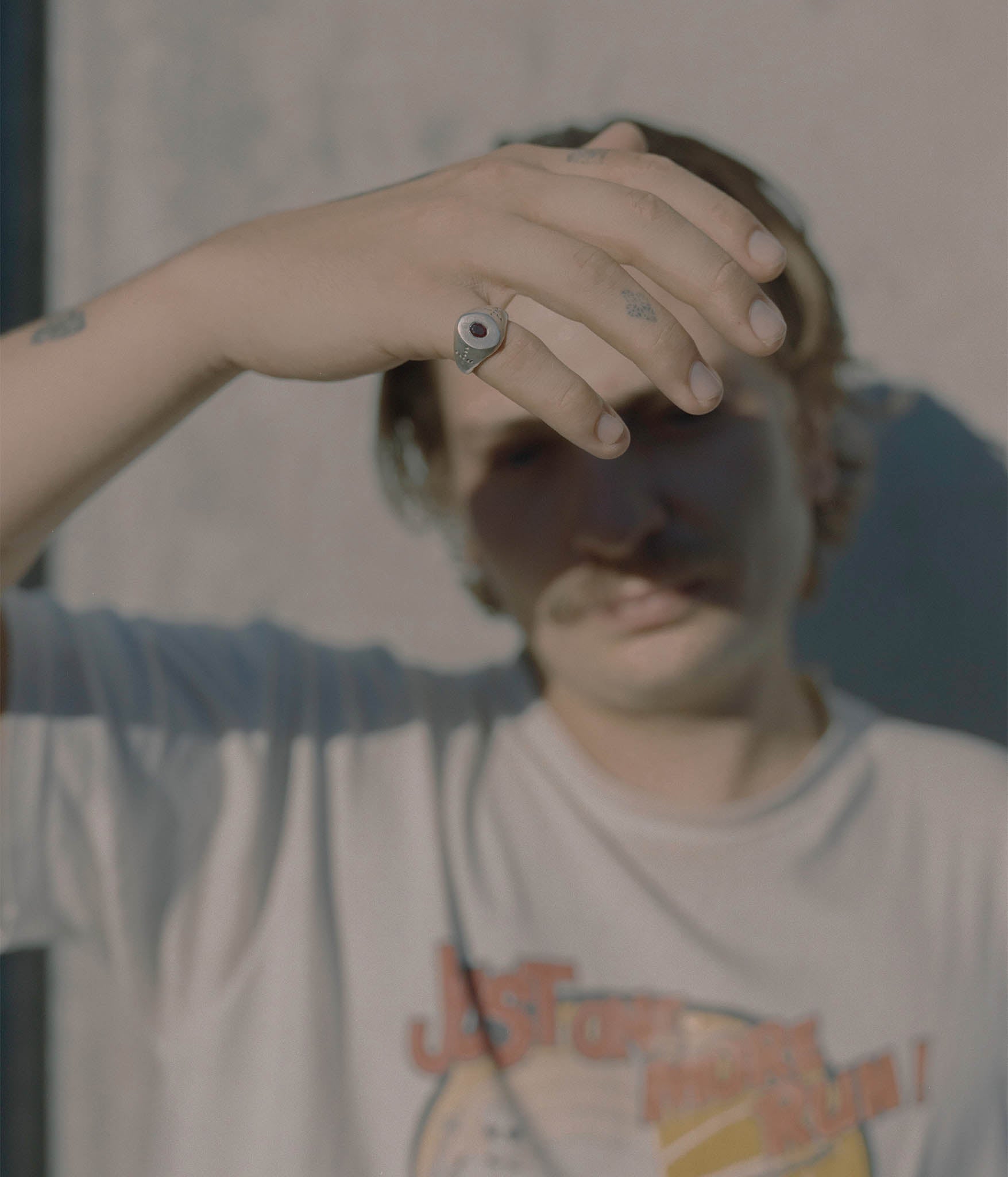 Person wearing a graphic t-shirt with text and design, holding hand up to face.