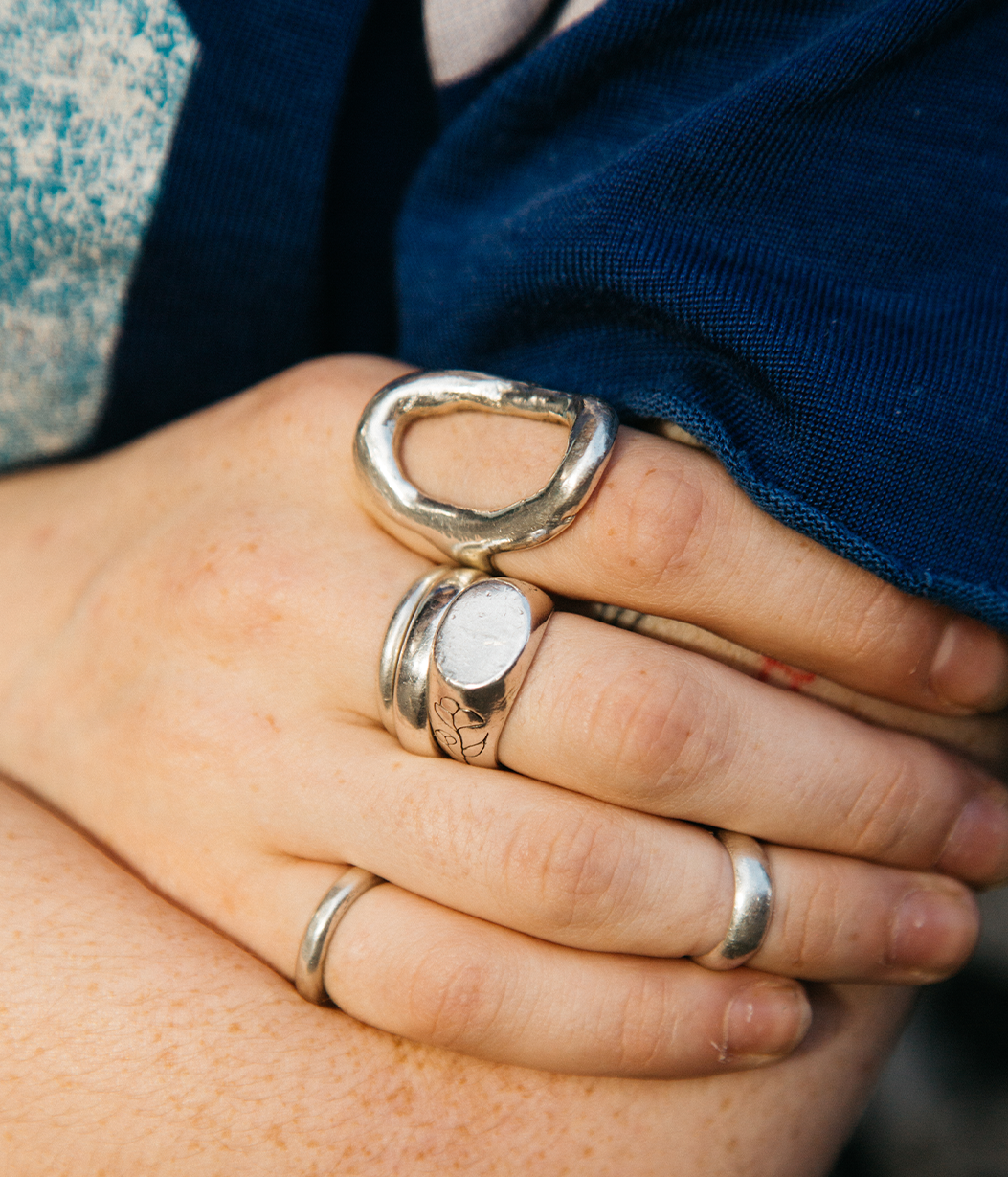 Close-up of a hand wearing multiple silver rings with a blurred background