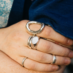 Close-up of a hand wearing multiple silver rings with a blurred background