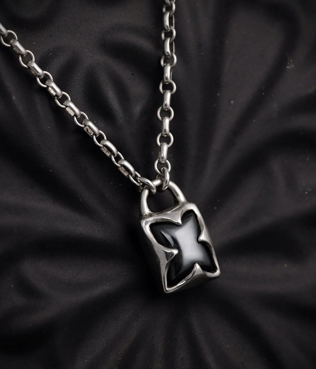 Silver padlock-shaped pendant on a chain against a black textured background