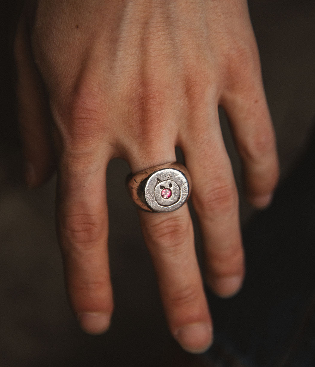 Hand wearing a ring with a circular design on a dark background