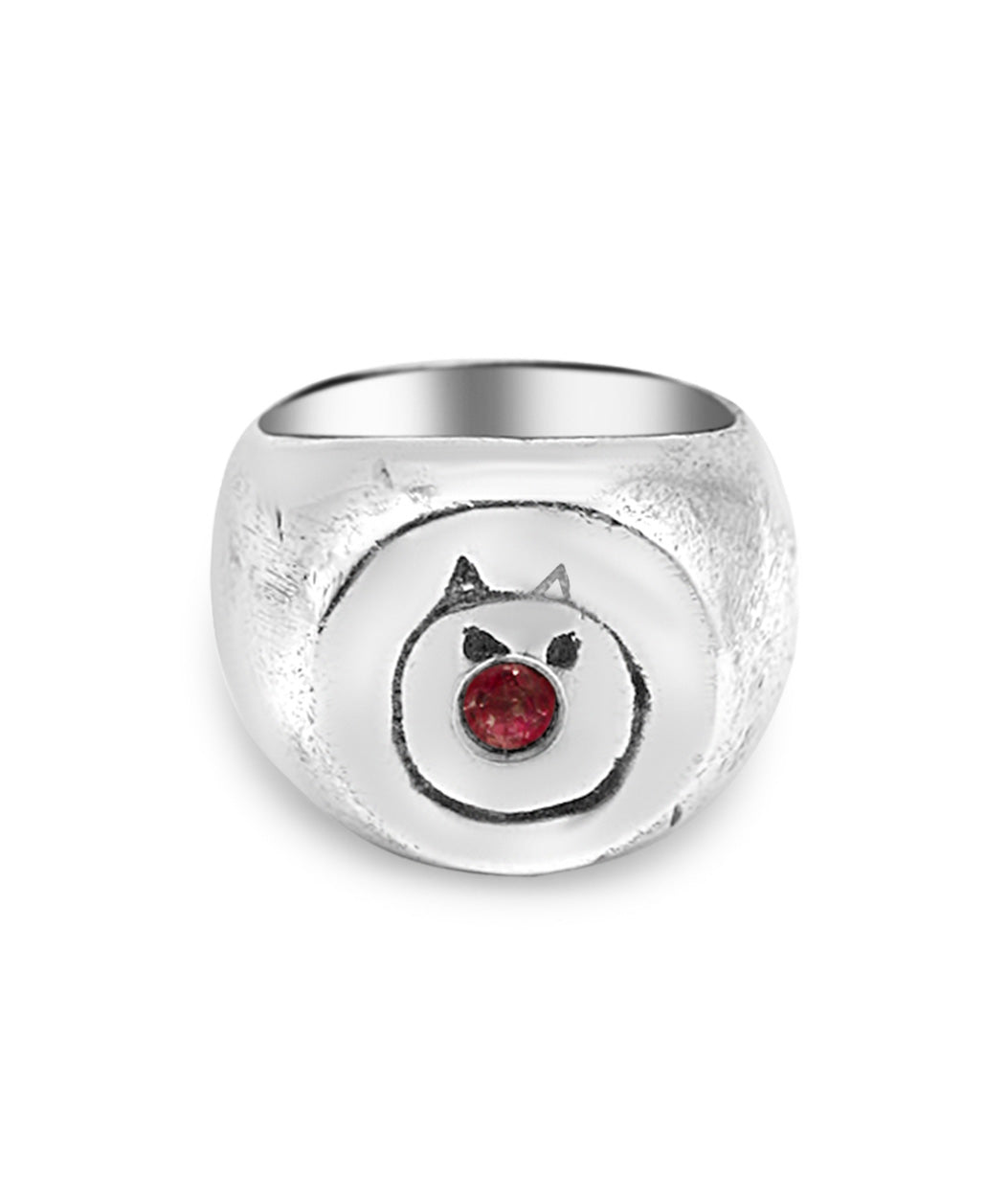 Silver ring with a face design and red gemstone on a white background
