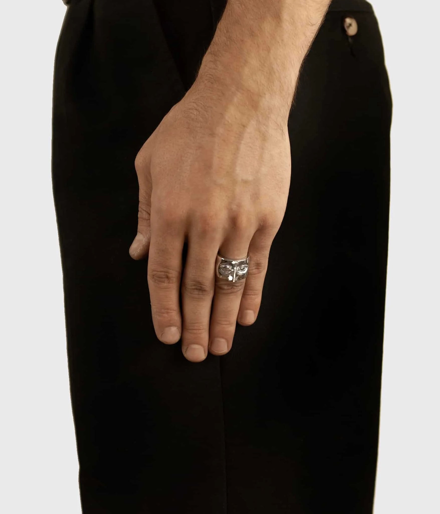 Hand wearing a silver ring on a plain background