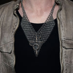 Person wearing a chainmail necklace with a dark background