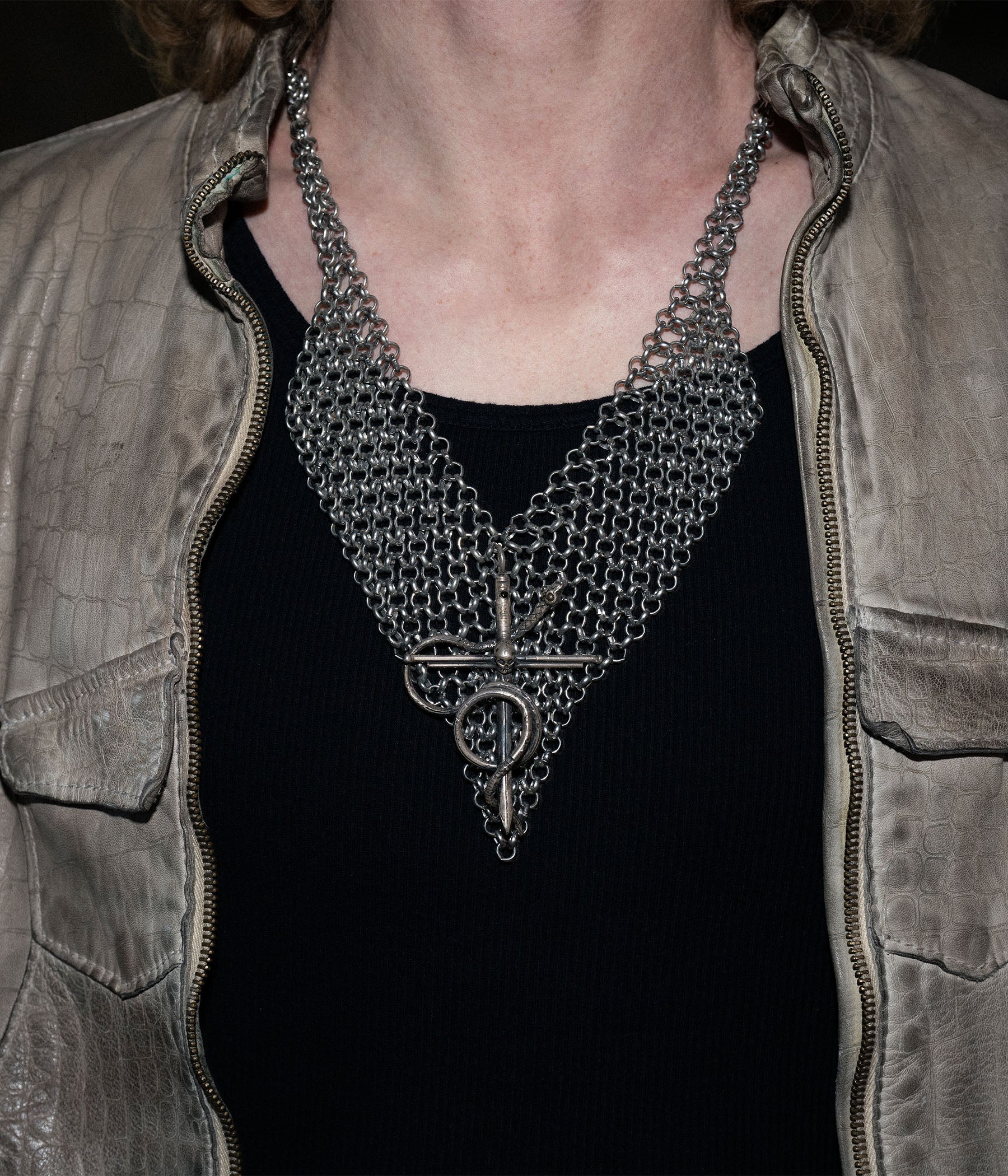 Person wearing a chainmail necklace with a dark background