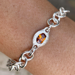 Silver bracelet with a central amber stone on a wrist.