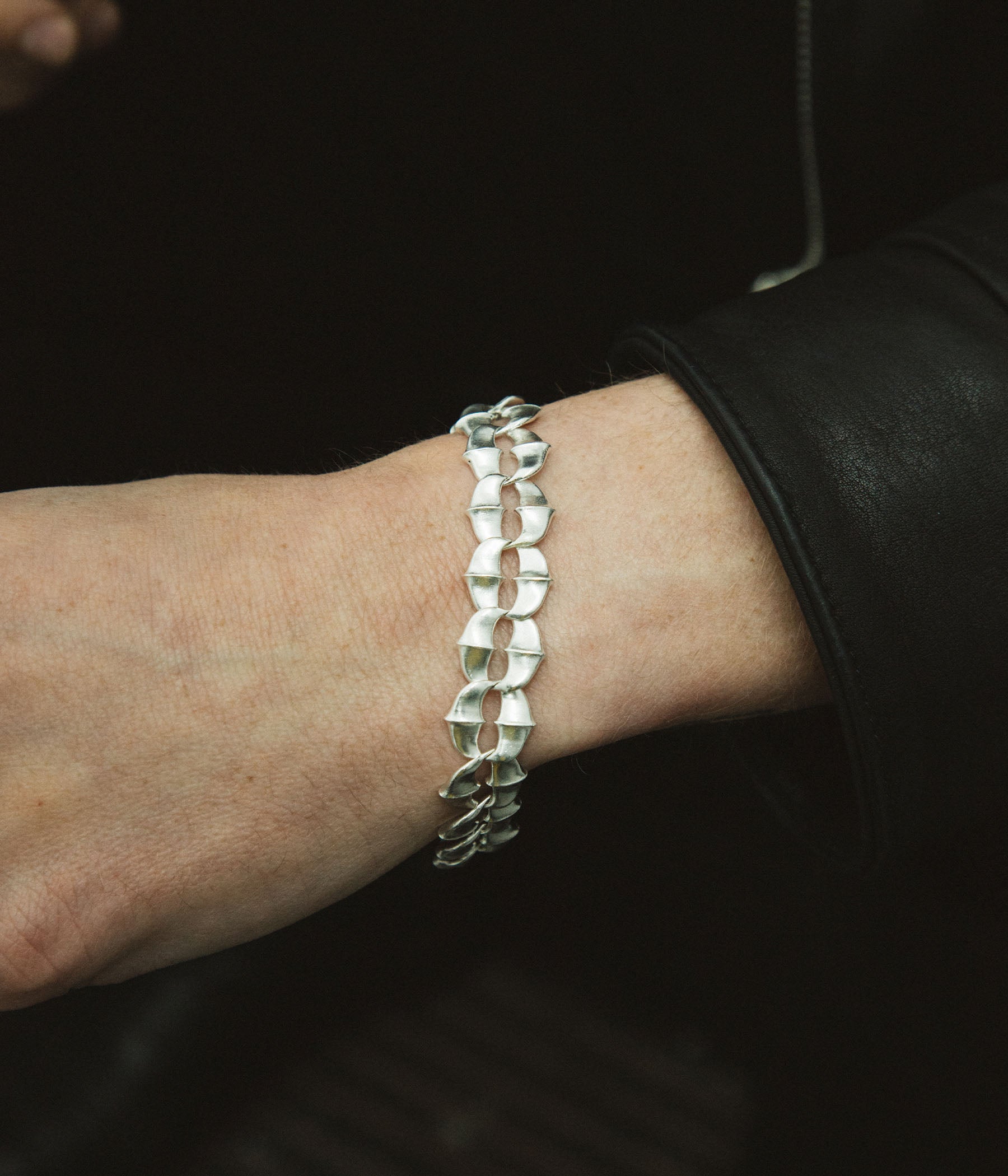 Silver bracelet on a wrist with a dark background