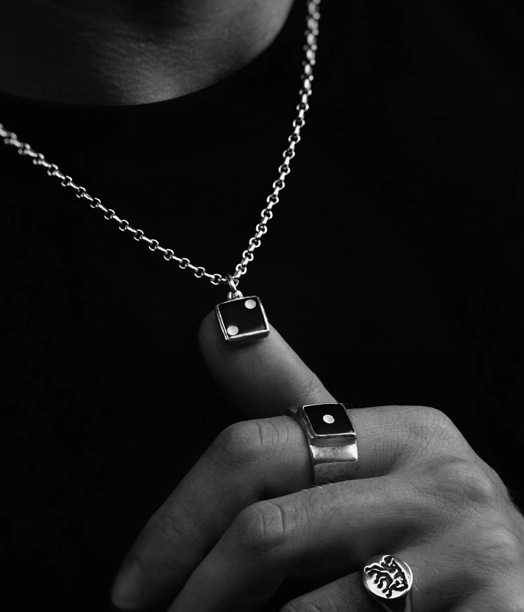 Close-up of a hand wearing multiple silver rings with a dark background