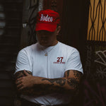 Person wearing a red 'Rodeo' cap and white t-shirt with '27 Canal Street' text, standing against a dark background.