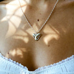 Necklace with a paw print pendant worn by a person, with a blurred background.