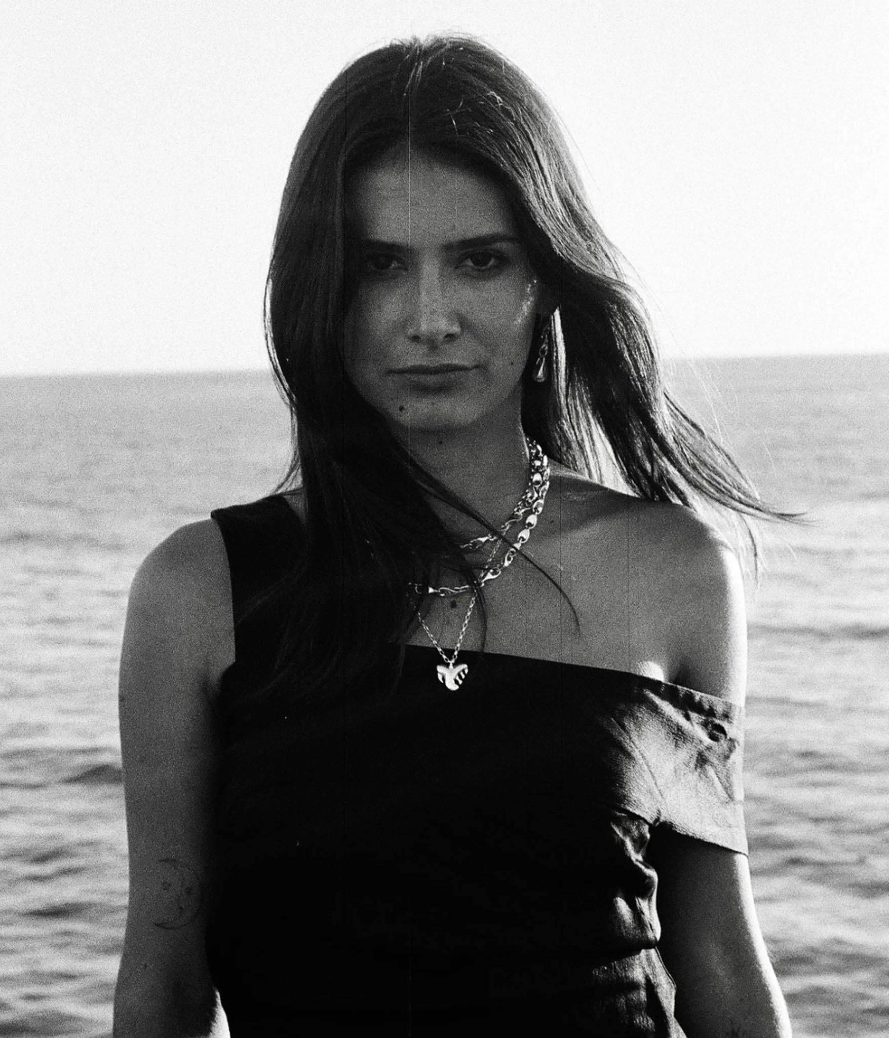 Black and white photo of a woman standing by the ocean