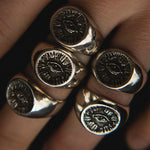 Close-up of a hand wearing multiple gold rings with eye designs.