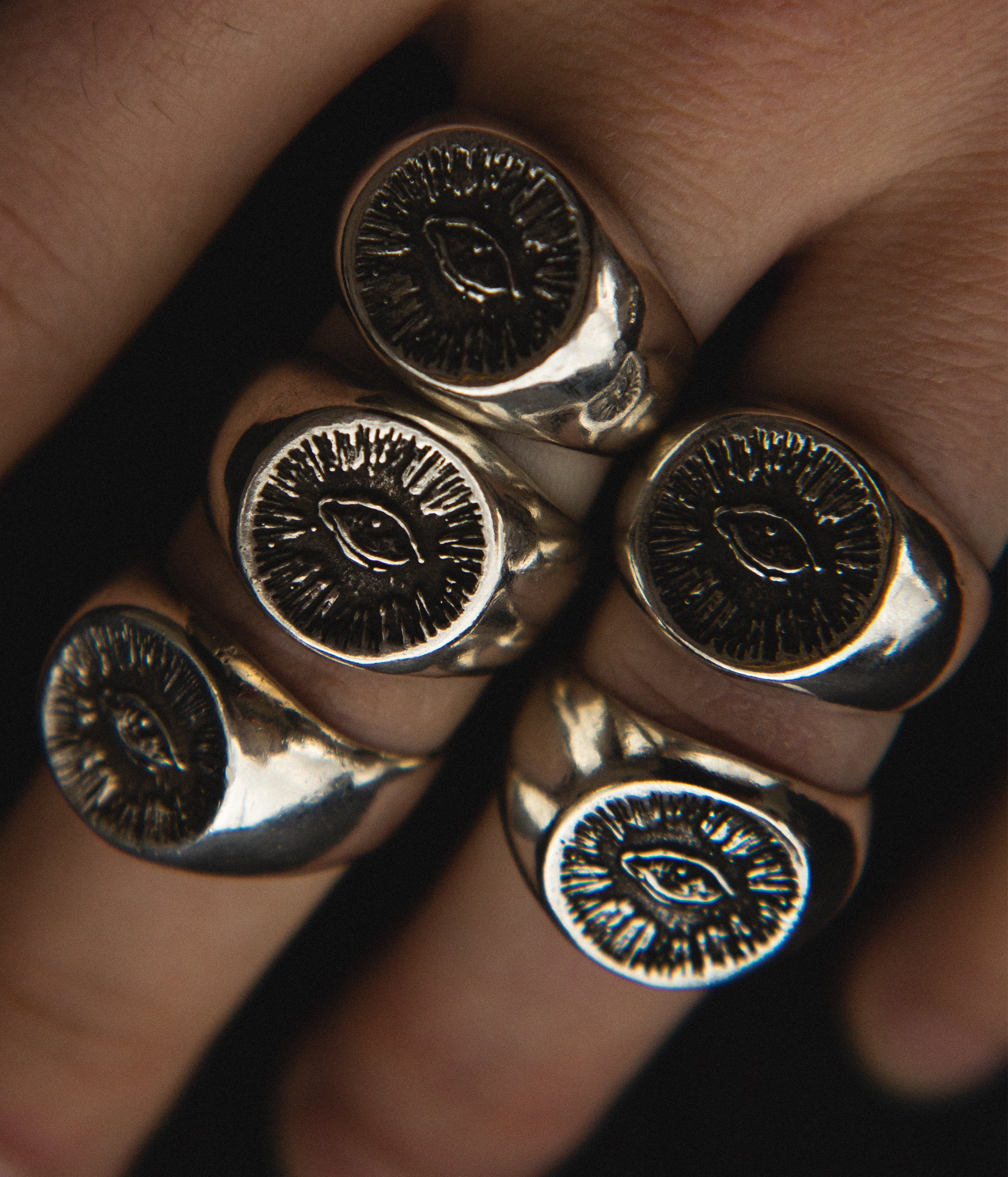 Close-up of a hand wearing multiple gold rings with eye designs.