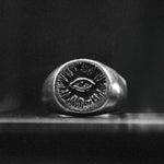 Silver ring with eye design on a dark background