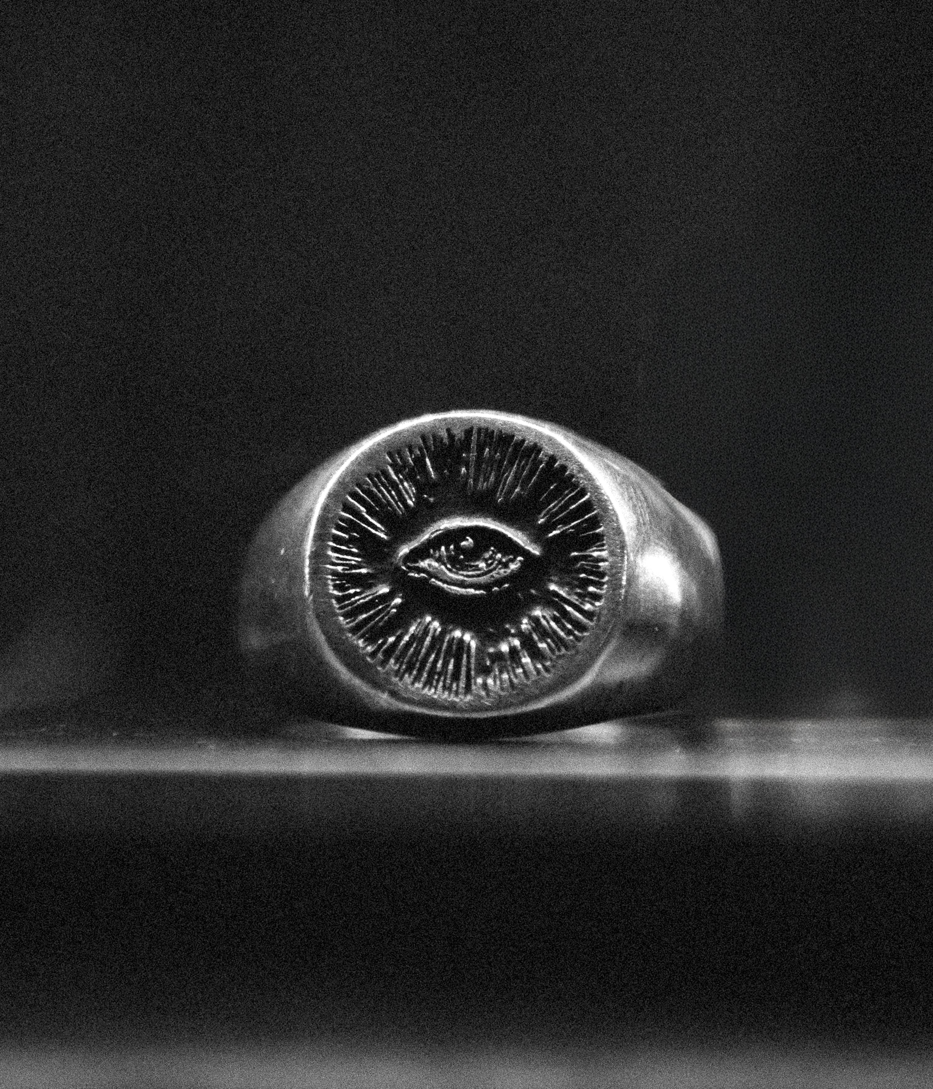 Silver ring with eye design on a dark background