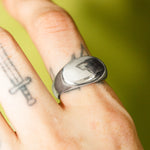 Silver ring on a finger with a green background
