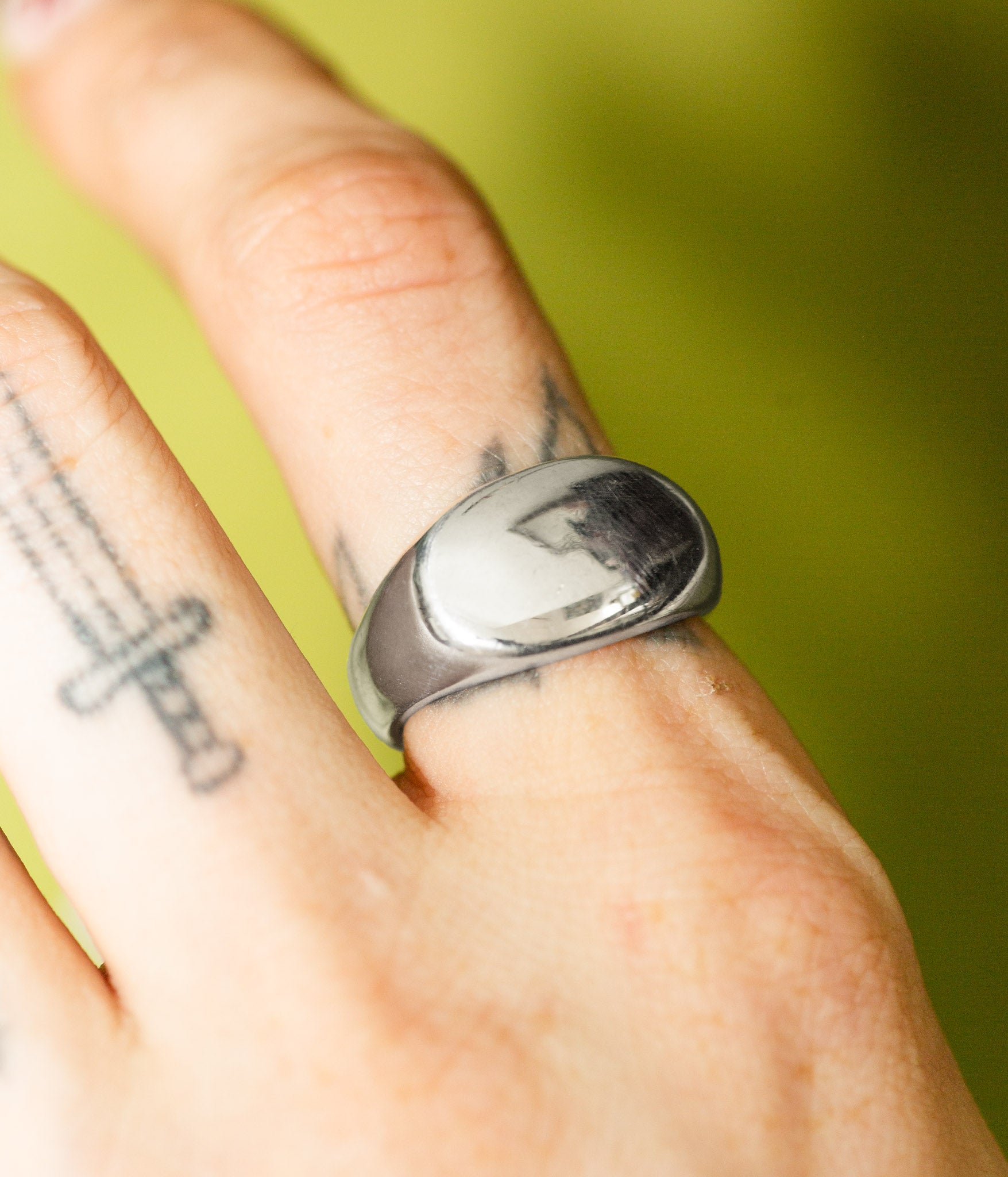 Silver ring on a finger with a green background