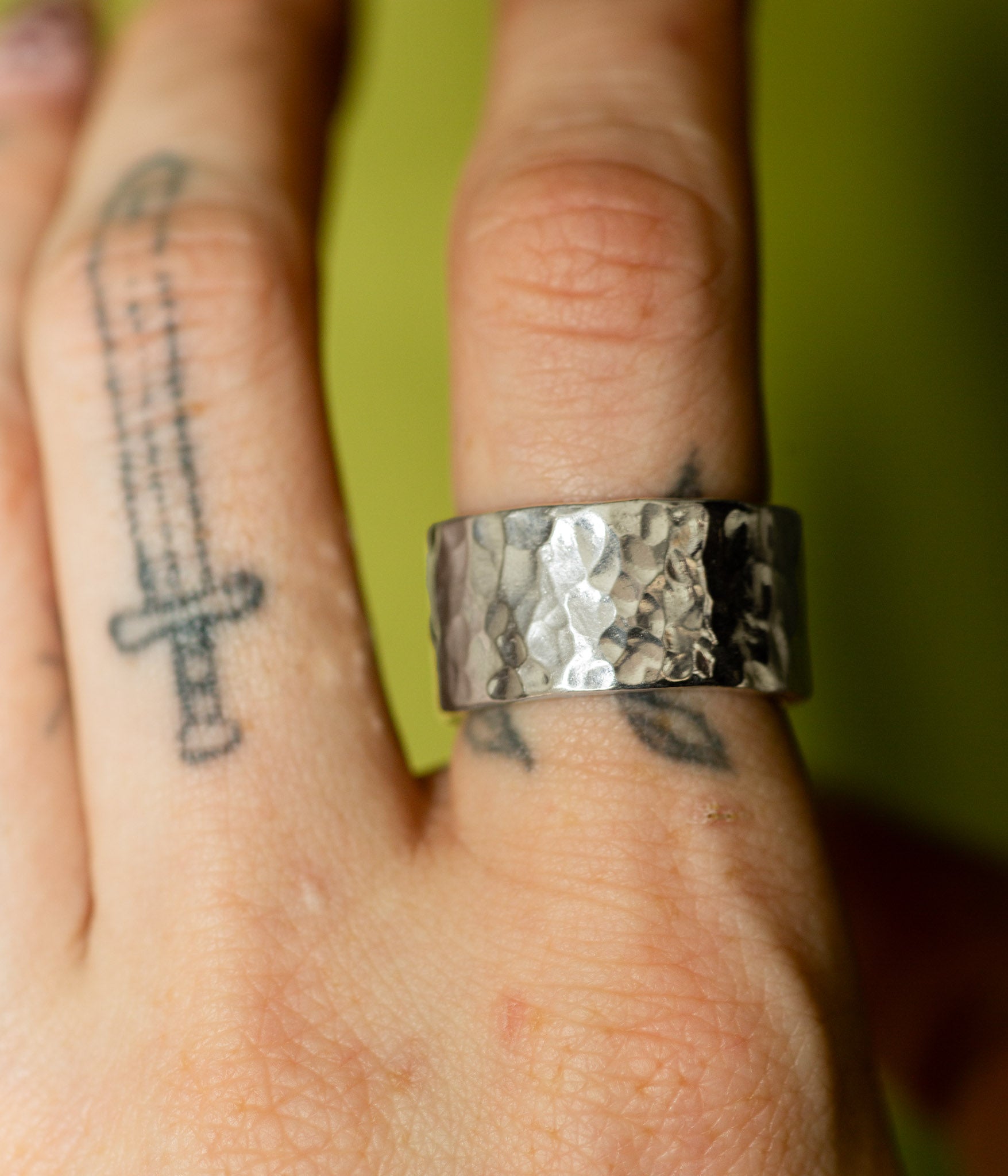 Silver ring on a finger with a green background