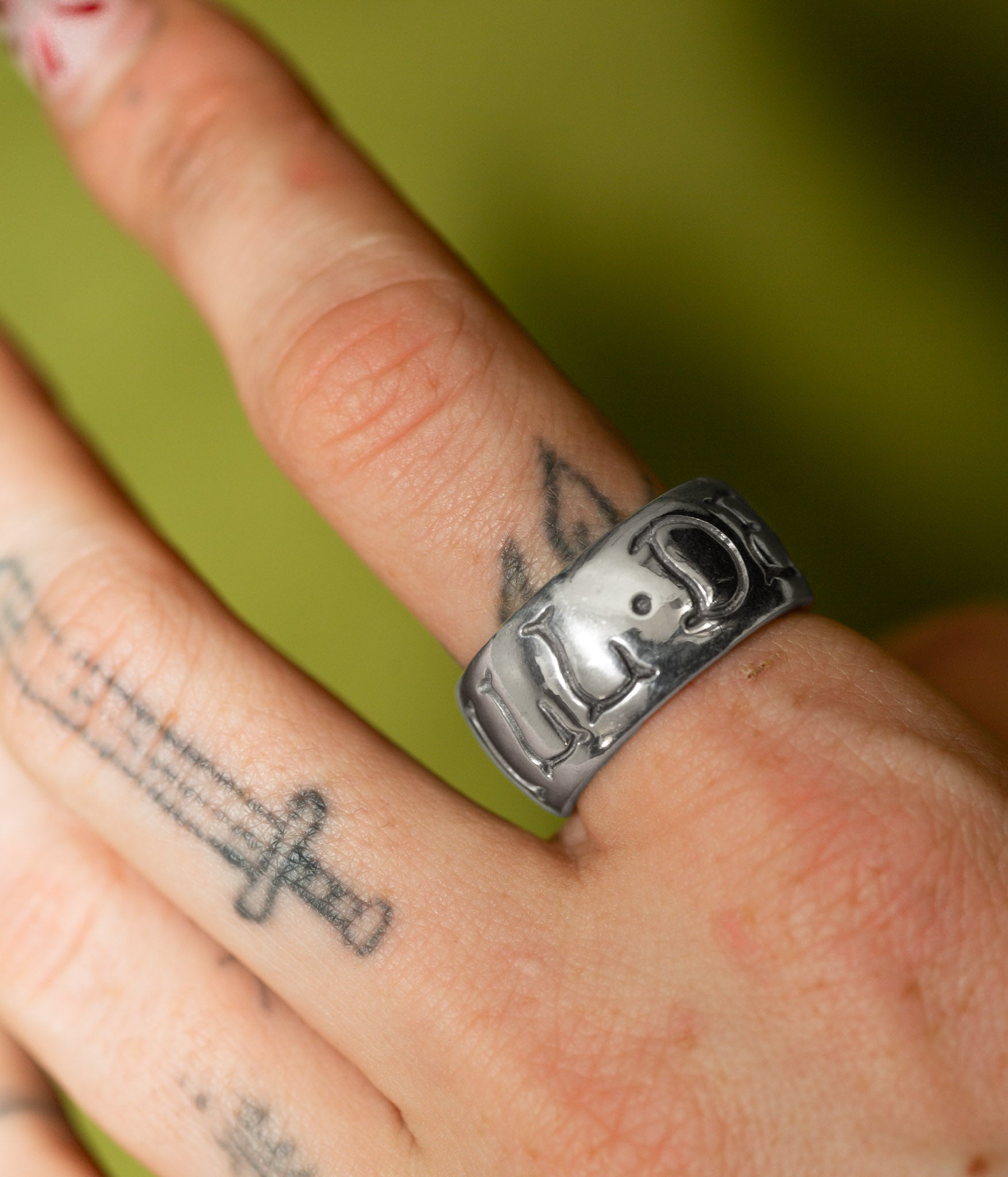 Silver ring with elephant design on a person's finger against a green background