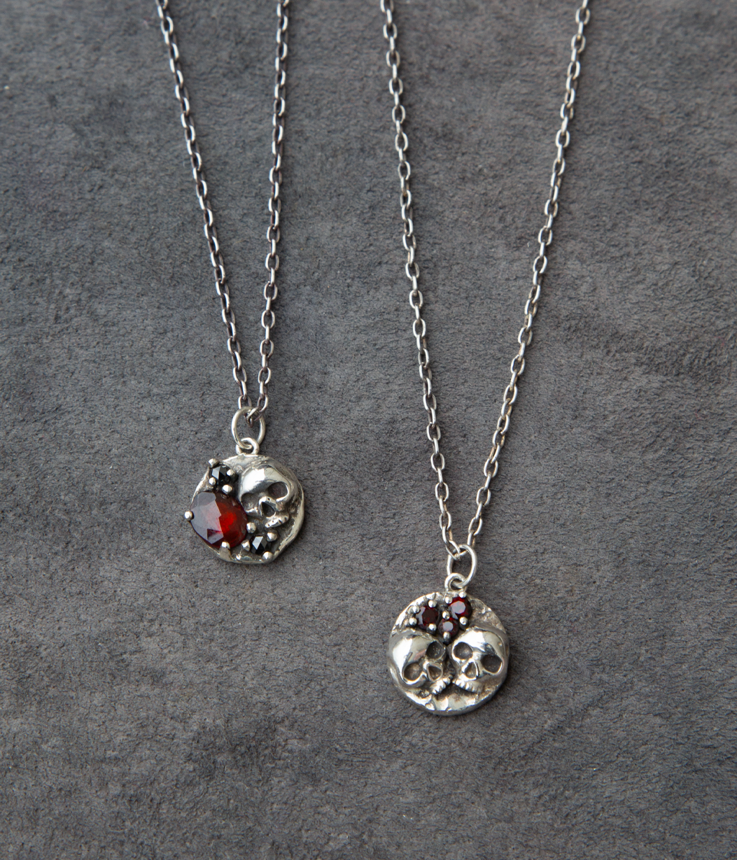 Two silver necklaces with circular pendants on a gray background