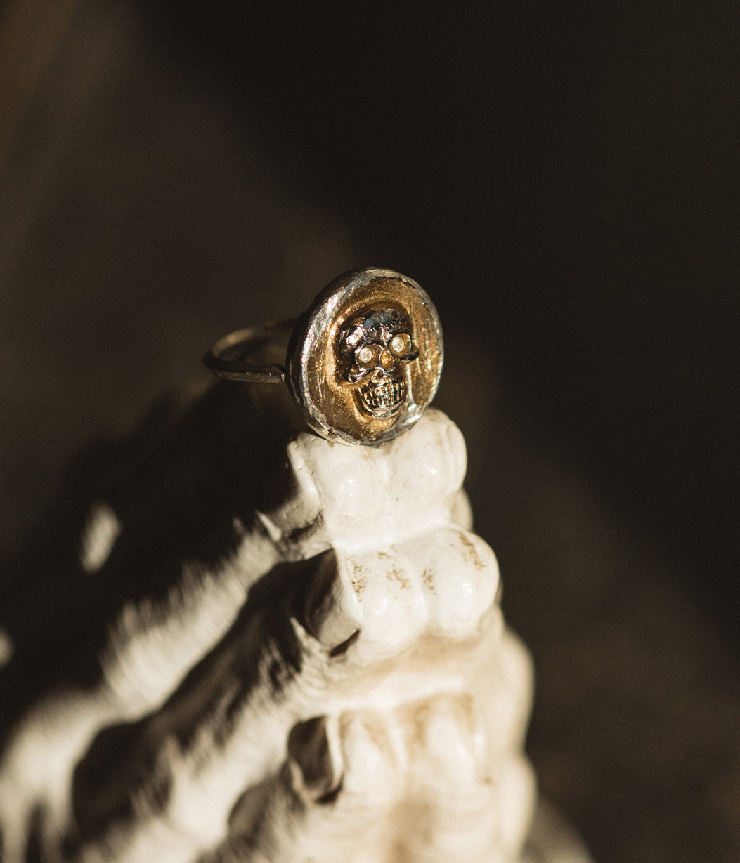 Close-up of a gold and silver ring on a reflective surface with a dark background