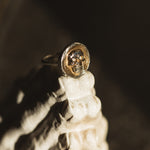 Close-up of a gold and silver ring on a reflective surface with a dark background