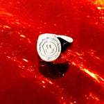 Silver ring with a smiley face design on a red background